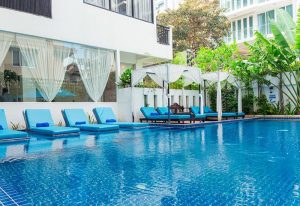 Home Chic Hotel's pool area. Gay-friendly hotel with blue loungers, white canopies, and lush greenery. A relaxing oasis for gay travelers.