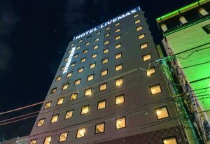 Hotel Livemax Shinjuku-Kabukicho exterior at night. Gay-friendly hotel in Tokyo, Japan. Modern building with illuminated windows.