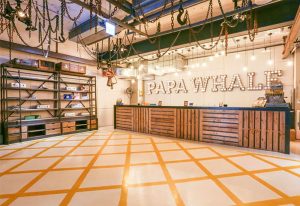 Hotel PaPa Whale's lobby. Gay-friendly hotel with a rustic design, featuring wooden reception desk, chains hanging from the ceiling and a display shelf.