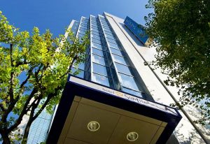 Hotel Sunlite Shinjuku, a gay-friendly hotel in Tokyo. Exterior view of the modern building with glass windows and a blue sign.