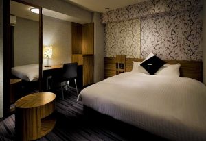 Hotel Villa Fontaine Tokyo-Shinjuku room. Modern interior, bed with white linens, desk, and floral wallpaper. Gay-friendly hotel in Shinjuku, Tokyo.
