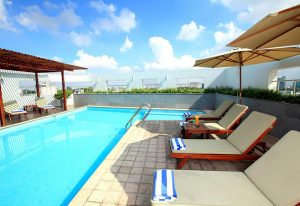 Liberty Central Saigon Centre Hotel's pool area. A gay-friendly hotel in Saigon, Vietnam. Loungers, umbrellas, and blue skies.