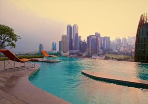 Manhattan Hotel's rooftop pool with city view. Gay-friendly hotel offers luxury with skyline views. Loungers by the infinity pool.