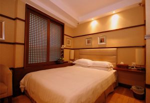 Mingle At The Eden, a gay-friendly hotel. Bedroom with double bed, wooden window frame, and warm lighting. Hotel room interior.