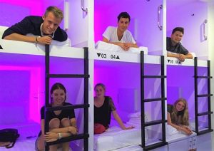 Gay-Friendly New Batavia Capsule Hotel: Guests relaxing in their capsule beds. A modern, social, and affordable lodging option for gay travelers.