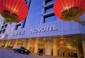 Novotel Beijing Xinqiao, a gay-friendly hotel. Exterior view with lanterns, a car, and people at the entrance. Beijing travel advice.