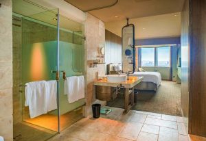 Palais de Chine Hotel gay-friendly room. Modern bathroom with shower, sink, and view of the bedroom. Luxury gay travel in Taiwan.