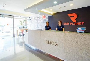 Red Planet Quezon Timog's reception area. Gay-friendly hotel with staff at the front desk. Modern design and clean space.