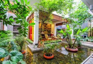Saravoan Royal Palace's gay-friendly hotel courtyard. Water feature with plants, stones, and lush greenery. Relaxing space for gay travelers.