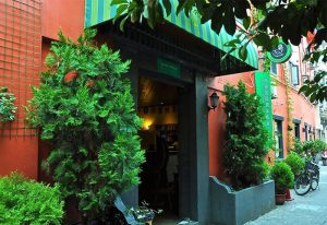 Entrance of Shanghai Le Tour Traveler's Rest Youth Hostel, a gay-friendly hotel in Shanghai. Exterior view with plants and an inviting doorway.