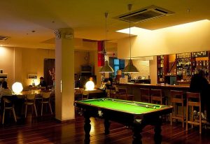 Shanghai Rock & Wood International Youth Hostel's common area with a pool table, bar, and seating. Gay-friendly hotel in Shanghai.