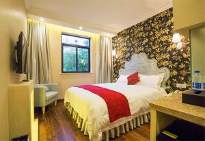Shanghai Soho Garden Hotel room. A gay-friendly hotel with a bed, floral wallpaper, and a window. Ideal for gay men's travel in Shanghai.