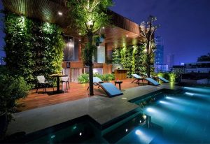 Silverland Yen Hotel's rooftop pool at night. This gay-friendly hotel features a modern design, lush greenery, and city views.