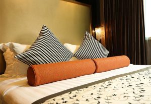 Sohotel gay-friendly hotel room: bed with patterned pillows and orange bolster. Comfortable lodging for gay travelers. Stylish interior.