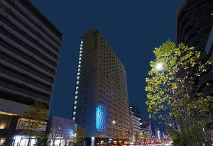 Sotetsu Fresa Inn Higashi Shinjuku at night. Gay-friendly hotel with modern architecture in Tokyo, Japan. Urban scene with city lights.