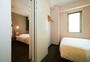 Super Hotel Shinjuku Kabukicho gay-friendly room. Compact, clean design. Bed, window, and closet space visible. Modern, comfortable stay.