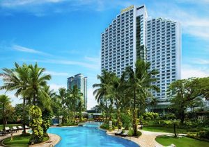 Swiss-Belhotel Mangga Besar exterior view. Gay-friendly hotel with pool, palm trees, and modern architecture in Jakarta, Indonesia.