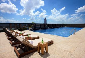 Rooftop pool at The Okura Prestige Taipei Hotel, a gay-friendly hotel. Lounge chairs, blue sky, and Taipei skyline. Ideal for gay men's travel.