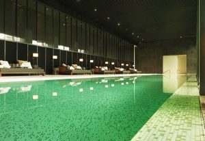 The PuLi Hotel and Spa's pool. Gay-friendly hotel with a green mosaic-tiled pool and lounge chairs. Luxury travel for gay men.