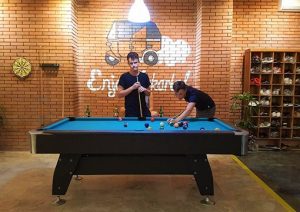 Gay-friendly Wonderloft Hostel: Two men play pool in the hostel's game room. Brick wall, tuk-tuk mural. Great for gay travelers.