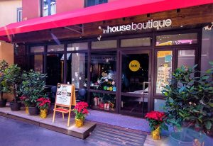 Inhouse Boutique, a gay-friendly hotel. Storefront view with red awning, plants, and Christmas decorations. Welcoming space for gay travelers.