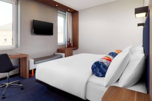 Aloft Munich room. Modern, gay-friendly hotel in Munich. Features a bed, desk, TV, and colorful decor. Great for gay travelers visiting Munich.