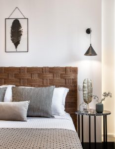 Amelot Art Suites gay-friendly hotel room. Woven headboard, feather art, side table with decor. Stylish design for gay travelers.