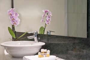 Arion Athens Hotel's gay-friendly bathroom. Sink, mirror, orchid, and toiletries create a welcoming space for LGBTQ+ travelers in Athens.