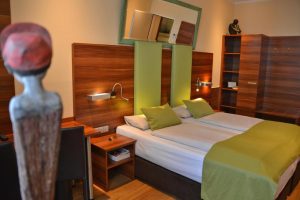 Arthotel Munich gay-friendly hotel room. Twin beds, green accents, wood paneling, and artful decor create a welcoming space for gay travelers.