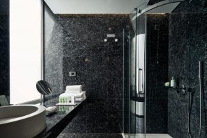 AthensWas Hotel's modern, gay-friendly bathroom. Dark marble, shower, sink, and towels create a luxurious experience for gay travelers.