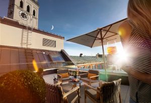 BEYOND by Geisel gay-friendly hotel rooftop terrace view. Munich hotel with champagne, seating, & city views. Gay travel advice.
