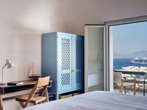 Belvedere Mykonos Hilltop Complex room. Gay-friendly hotel view: desk, blue closet, balcony, and cruise ship. Mykonos travel advice.
