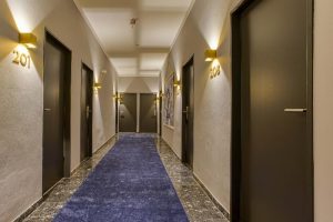 Hallway at Boutique Hotel 026 Köln St. Michael, a gay-friendly hotel. Blue carpet, room numbers, and modern design. Köln gay travel advice.