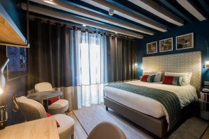 Hotel Indigo Milan Corso Monforte, gay-friendly hotel room. Bed, chairs, and blue walls. Stylish design for gay travelers.