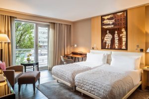 Le Méridien Munich gay-friendly hotel room. Twin beds, desk, chair, balcony, and modern decor. A comfortable stay for gay travelers in Munich.