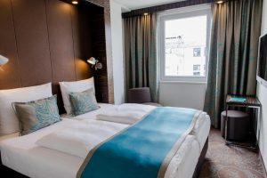 Motel One München Sendlinger Tor room. Gay-friendly hotel room with twin beds, blue accents, and modern design. Munich hotel for gay travelers.