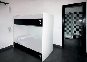 New Generation Hostel Milan Center gay-friendly room. Bunk beds and bathroom with black and white checkered tiles.