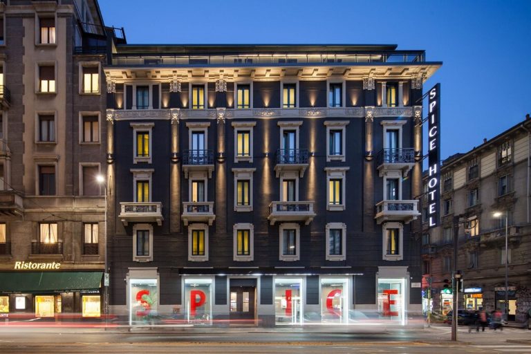Exterior view of the gay-friendly Spice Hotel Milano at dusk. Facade with illuminated windows and Spice Hotel sign. Modern design in Milan.