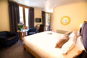 The Clarence, a gay-friendly hotel: Bedroom with double bed, seating area, desk, and TV. A comfortable space for gay men travelers.