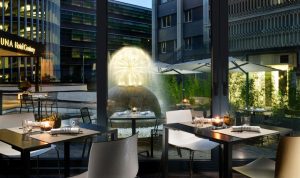 UNAHOTELS Century Milano gay-friendly hotel dining. Tables set near a water fountain. Milan hotel for gay travelers.