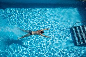 Man swimming in the pool at Purple Hotel, Ibiza. Gay adults-only hotel. Special gay travel destination. Top view.