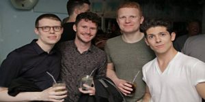 Four smiling gay men pose with drinks at The Friendly Society gay bar. A fun night out for gay travelers. Friendly-Society-Gay-Bar.jpg
