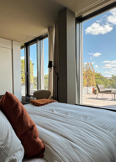 Das Stue Hotel room in Berlin. Modern luxury with a bed, large windows, and a balcony view. Popular gay hotel on TikTok, perfect for queer travel.