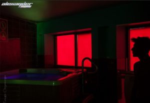 Alexander Sauna men's club: Interior shot of a hot tub with a silhouette of a man in front of a window with red light. Gay sauna travel.