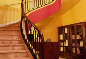 Ira Baths Athens: Interior view of a spiral staircase with wooden banister, leading up in a building in Athens. Gay travel advice.