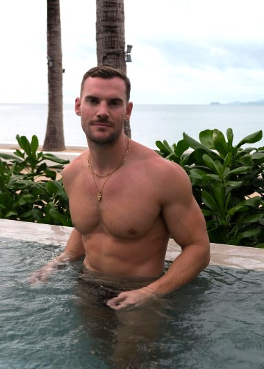 Gay man at Explorar Koh Samui Resort & Spa, an adults-only hotel. He's in a pool with a sea view, enjoying his vacation.