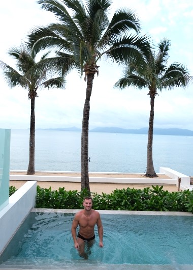 Gay Koh Samui resort: Muscular man in pool at Explorar Adults Only Resort and Spa. Beachfront hotel with palm trees. Best gay hotels.