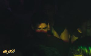Man at UNLEASH, top gay event in Singapore. Go-go dancers and influencer dancers create a vibrant nightlife experience. Dark, intimate setting.