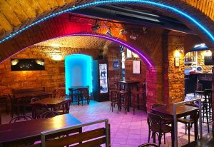 Klub 21 Prague interior. Gay bar with brick arches, neon lighting, tables, and bar stools. Prague gay travel advice.
