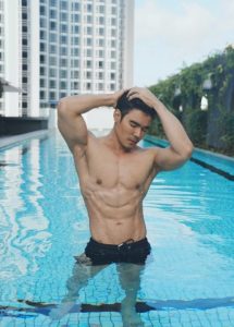 M Social Singapore rooftop pool view. Muscular man relaxing at top LGBT hotel near gay bars. Singapore gay travel advice.